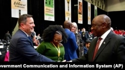 O Presidente sul-africano Cyril Ramaphosa, à direita, cumprimenta o líder da oposição da Aliança Democrática (DA), John Steenhuisen, à esquerda, na primeira sessão do Parlamento desde as eleições, na Cidade do Cabo, em 14 de junho de 2024.
