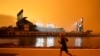 FILE - A jogger runs along McCovey Cove outside Oracle Park in San Francisco, under darkened skies from wildfire smoke on Sept. 9, 2020. 