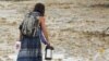 A Burning Man participant makes their way through the mud in Black Rock City, in the Nevada desert, after a rainstorm turned the site into mud, Sept. 2, 2023. 
