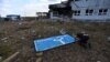 This photo taken Aug. 16, 2024, during a media tour organized by Ukraine, shows a man examining a damaged road sign with arrows to Ukraine and Russia, at a destroyed border crossing near the Ukraine-held town of Sudzha, in Russia's Kursk region.