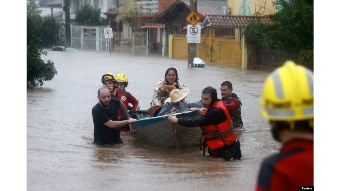 FILE - Rescue workers evacuate a family with a pet from a flooded area in the Cavalhada neighborhood in Porto Alegre, Brazil, May 23, 2024.