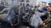 People and Lebanese army members stand near a burned car after an Israeli strike on the outskirts of the southern port city of Sidon, according to two Palestinian sources, in Lebanon, Aug. 21, 2024. 