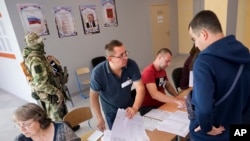 Точна кількість фіктивних «міжнародних спостерігачів», які взяли участь у російських псевдовиборах на окупованих територіях України, наразі невідома. Фото: озброєний солдат під час місцевих виборів в окупованому Росією Маріуполі, 10 вересня 2023 року