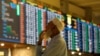 FILE - A stock broker reacts while monitoring the market on the electronic board displaying share prices during trading session at the Pakistan Stock Exchange, in Karachi, Pakistan, July 3, 2023.