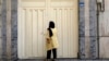 A woman reads the Iranian police closure notice on the gate of a language institute certified by the German embassy, in northern Tehran, Iran, Aug. 20, 2024. 