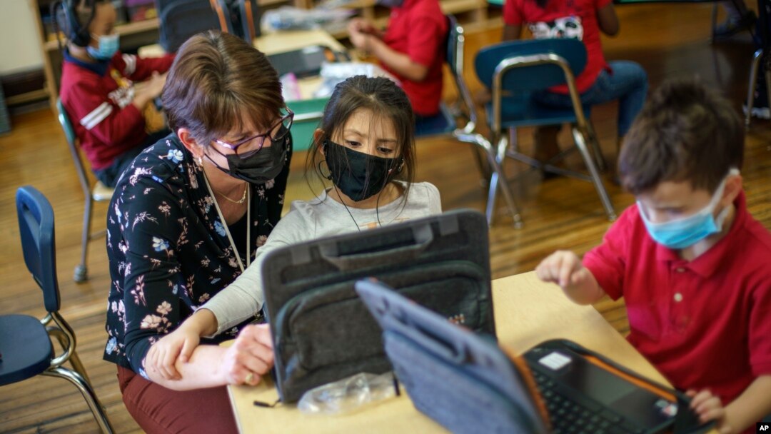 Kindergarten teacher Karen Drolet, left, works with a student at Raices Dual Language Academy, a public school in Central Falls, R.I., Feb. 9, 2022. (AP Photo/David Goldman, File)