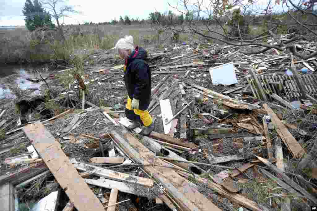 Tricia Burke walks over debris which washed up onto her property in the wake of superstorm Sandy, Nov. 1, 2012, in Brick, N.J.