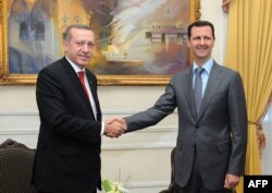 FILE - Syrian President Bashar al-Assad, right, shakes hands with Turkish Prime Minister Recep Tayyip Erdogan during a meeting in Aleppo, Feb. 6, 2011. (Photo by SANA / AFP)
