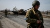 A Ukrainian serviceman stands near the wreck of a Russian tank on the front line in the Kyiv region, Ukraine, March 28, 2022. 