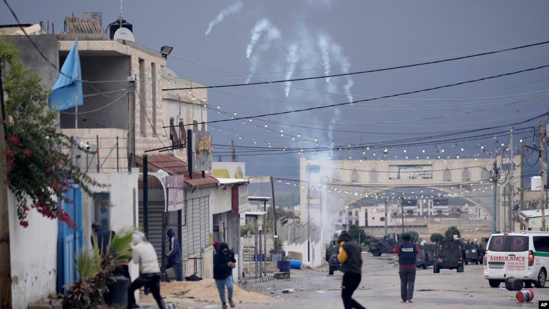 Palestinians run from tear gas fired by Israeli forces raiding Aqbat Jabr camp, southwest of the city of Jericho on Feb. 4, 2023, during a search for the Palestinian suspects behind a shooting attack in a nearby settlement last week.