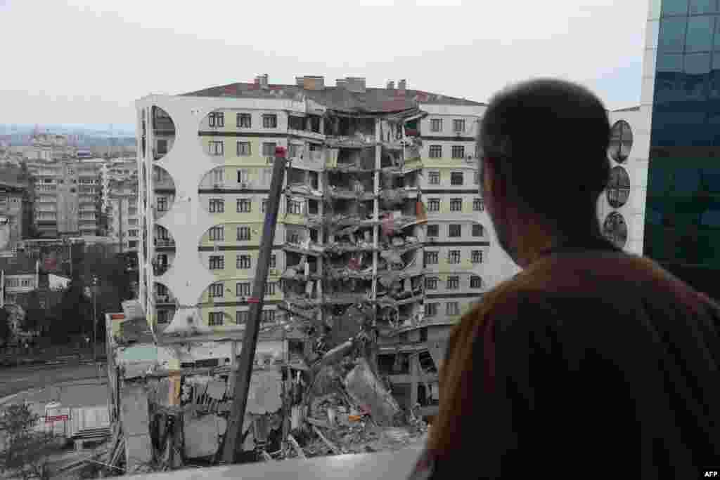 A man looks on at search and rescue operations conducted in the rubble of a collasped building, in Diyarbakir, Feb. 6, 2023,