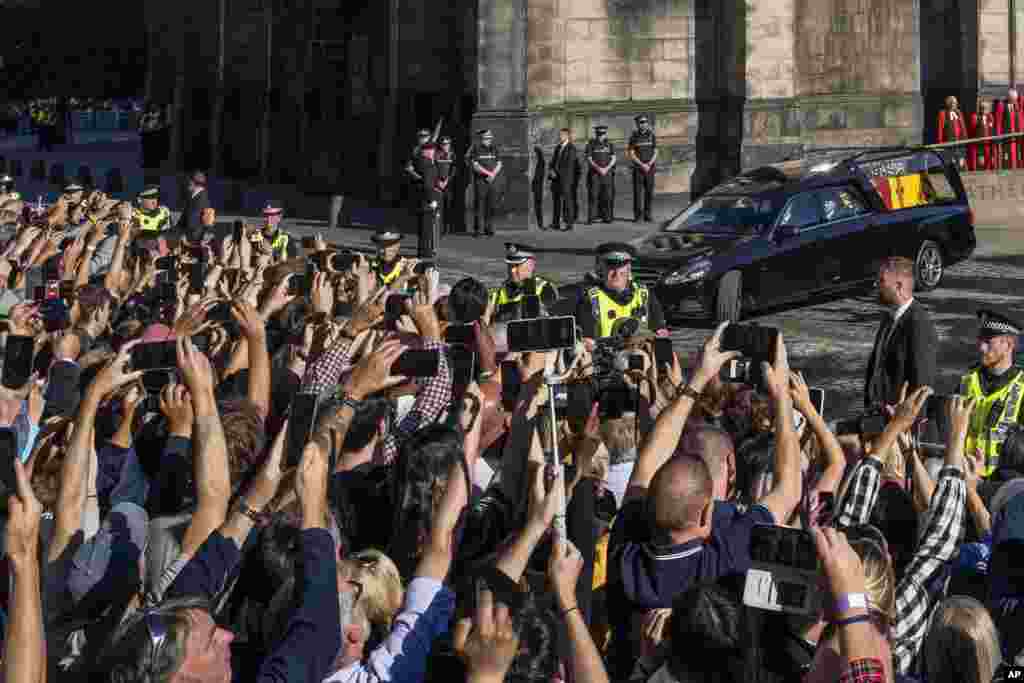 People take photos with their mobile phones as the Queens cortege with the hearse carrying Queen Elizabeth's coffin departs from St. Giles Cathedral en route to Edinburgh Airport in Edinburgh, Sept. 13, 2022.