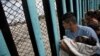 A member of the Central American migrant caravan, holding a child, looks through the border wall toward a group of people gathered on the U.S. side, as he stands on the beach where the border wall ends in the ocean, in Tijuana, Mexico, April 29, 2018. 