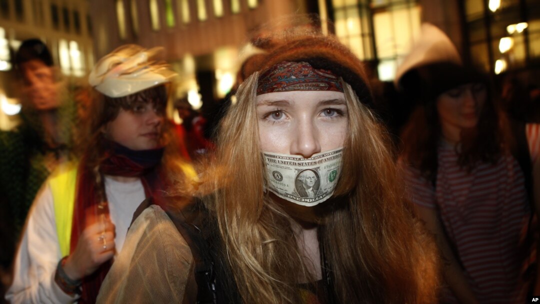 A woman dances with a US dollar covering her mouth during a protest against government austerity measures in central London November 30, 2011.