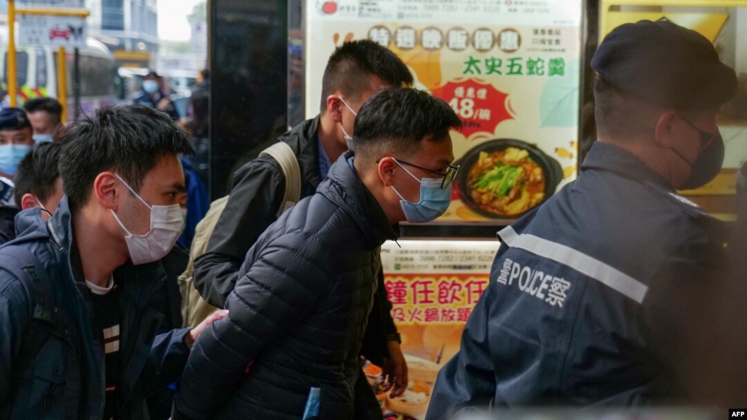 FILE - Stand News chief editor Patrick Lam (center) is brought to the news outlet's office building in handcuffs after police were deployed to search the premises in Hong Kong's Kwun Tong district on December 29, 2021.