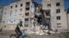 A man rides a bicycle past a building damaged in Russian shelling in Bakhmut, Donetsk region, Ukraine, Monday, June 20, 2022. 