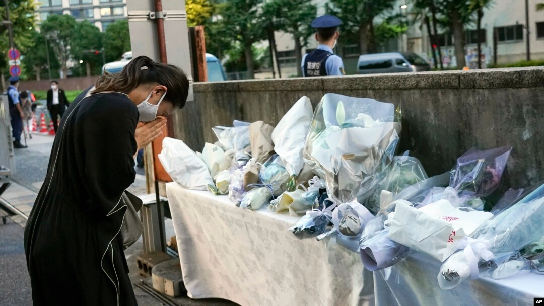 A mourner offers a flower for former Japanese Prime Minister Shinzo, at the entrance of the Liberal Democratic Party (LDP) headquarters building in Tokyo, Japan, July 10, 2022. 