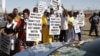 A group of protestors holds placards as a large crowd follows retired judge Ian Farlam and his team as they inspect the area where the bodies of mine workers were found after the shootings at Lonmin's platinum mine in Marikana near Rustenburg, South Africa, October 1, 2012.