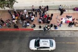 FILE - In this Nov. 10, 2019, photo, migrants gather at the U.S.-Mexico border in Tijuana, Mexico, to hear names called from a waiting list to claim asylum in the U.S.