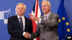 FILE - EU chief Brexit negotiator Michel Barnier, right, welcomes British Secretary of State David Davis for a meeting at the EU headquarters in Brussels, July 17, 2017. The British government is fighting back against criticisms that it is divided and unprepared for Brexit.
