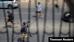 Pro-democracy protesters and a journalist run as riot police officers advance them during a rally against the military coup in Yangon, Myanmar, Feb. 27, 2021.