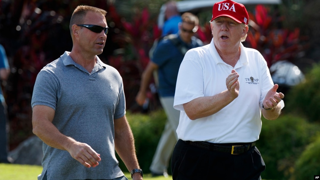 FILE - President Donald Trump walks with Gene Gibson, commanding officer at Coast Guard Station Lake Worth Inlet, as he arrives, Dec. 29, 2017, to meet with members of the U.S. Coast Guard, who he invited to play golf, at Trump International Golf Club, in West Palm Beach, Fla. 