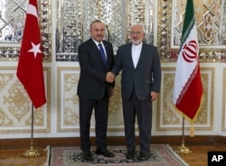 Iranian Foreign Minister Mohammad Javad Zarif, right, and his Turkish counterpart Mevlut Cavusoglu shake hands for journalists at the start of their meeting, in Tehran, Iran, Feb. 7, 2018.