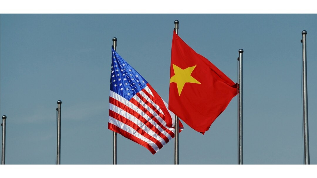 The U.S. flag (L) flutters next to the Vietnamese flag in Hanoi, Vietnam June 1, 2015.