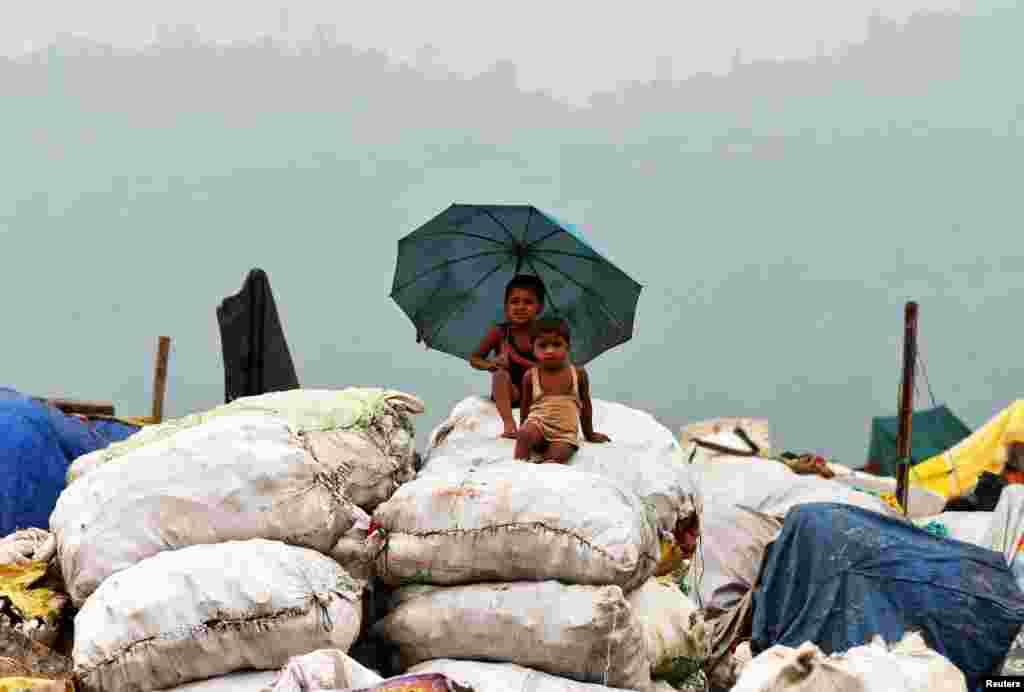 Children sit on sacks filled with recyclable material at a garbage dumping site in Guwahati, India.