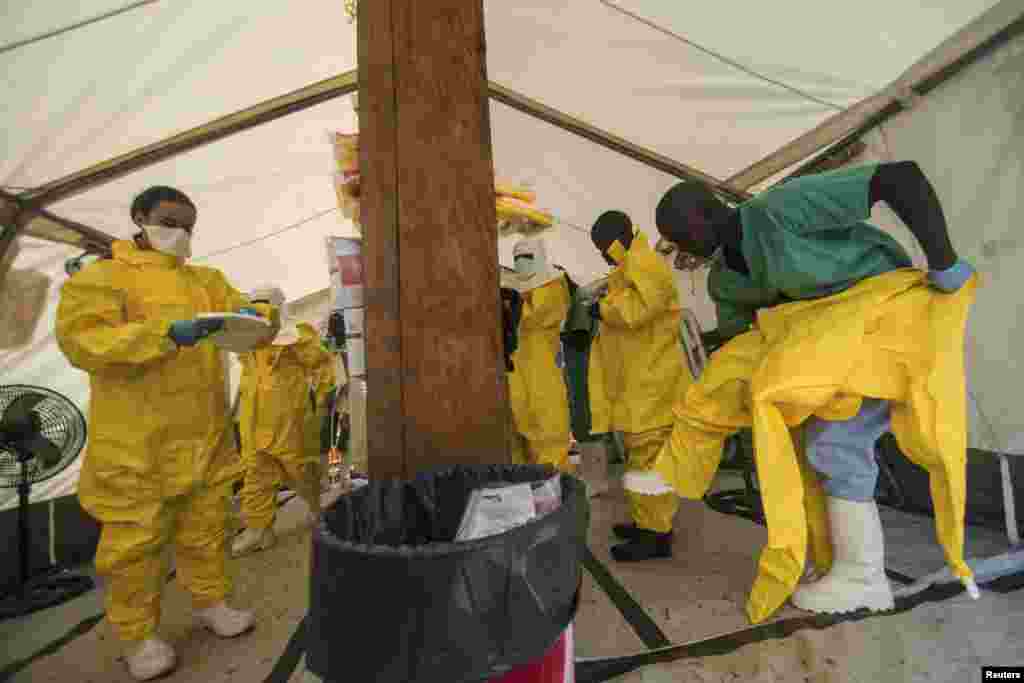 Syerra-Leonedagi klinikalardan birida xodimlar Ebola bilan kasallangan bemorlarga xizmat ko'rsatishdan oldin maxsus himoya kiyimlarini kiymoqda, 20-iyul, 2014-yil. 