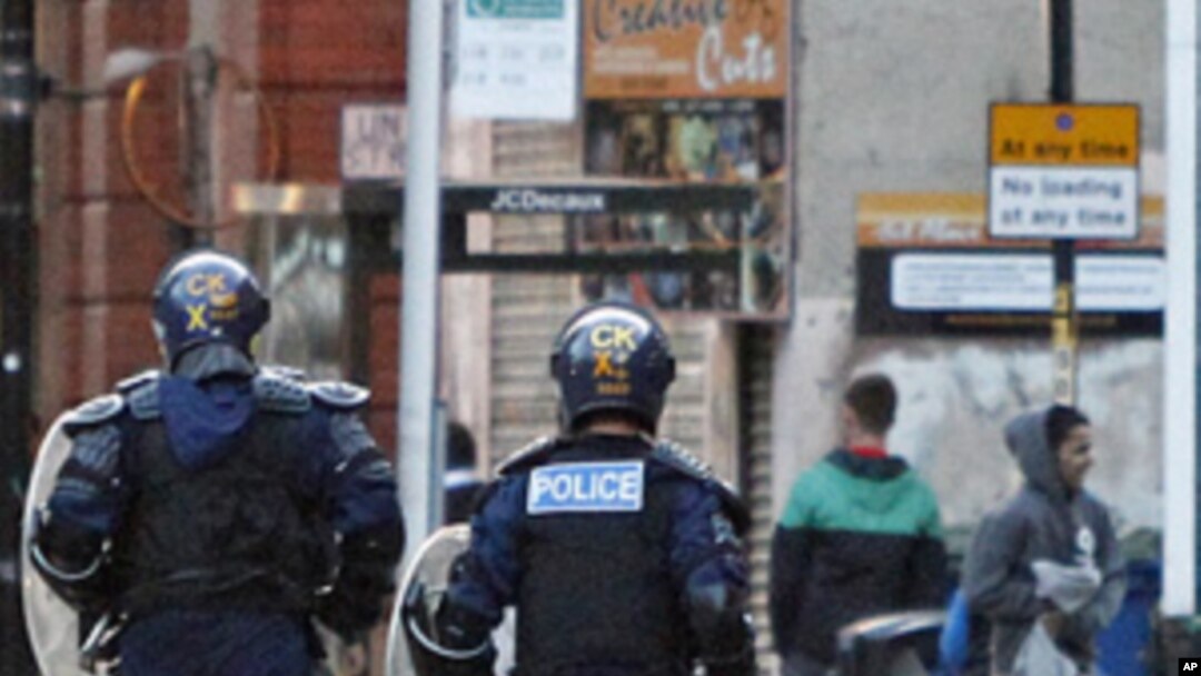 Riot police chase alleged looters during civil disturbances in Manchester, England, Aug. 9, 2011
