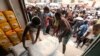 Workers unload sacks of wheat flour as people gather outside an aid distribution center in the Red Sea port city of Hodeida, Yemen, June 14, 2018. 