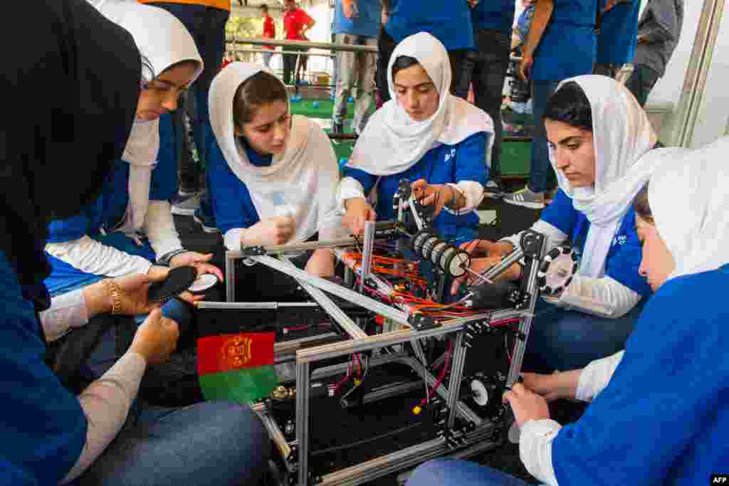 Members of the Afghan all-girls robotics team make adjustments to the team robot in Washington, DC.