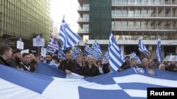 Protesters hold a Greek flag during a rally against the use of the term "Macedonia" in any settlement to a dispute between Athens and Skopje over the former Yugoslav republic's name, in Athens, Greece, Feb. 4, 2018. 