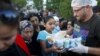 FILE - Syrian migrants queue to get food from a local NGO on the side of a highway near Edirne in Turkey, as they rest from their travel towards the Greek border, Sept. 17, 2015. 