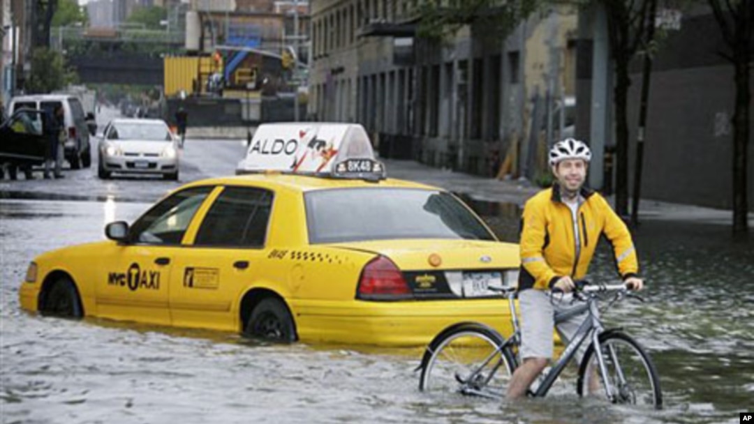 A bicyclist makes his way past a stranded taxi on a flooded New York City Street as Tropical Storm Irene passes through the city, August 28, 2011. A global warming-fueled sea level rise over the next century could flood millions in the US, according to a
