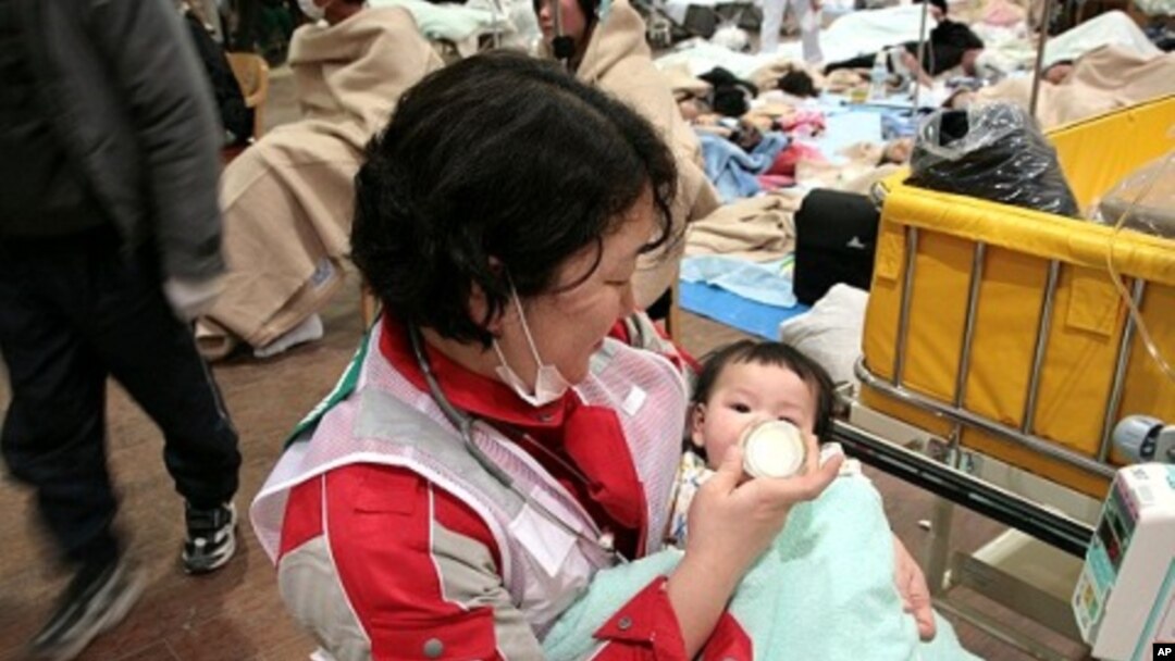 Japanese Red Cross Society worker feeds baby at relief center