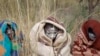 Xhosa boys covered with a blankets and smeared with chalky mud sit in a field as others undergo a traditional male circumcision ceremony into manhood near the home of former South African president Nelson Mandela in Qunu, South Africa, June 30, 2013.