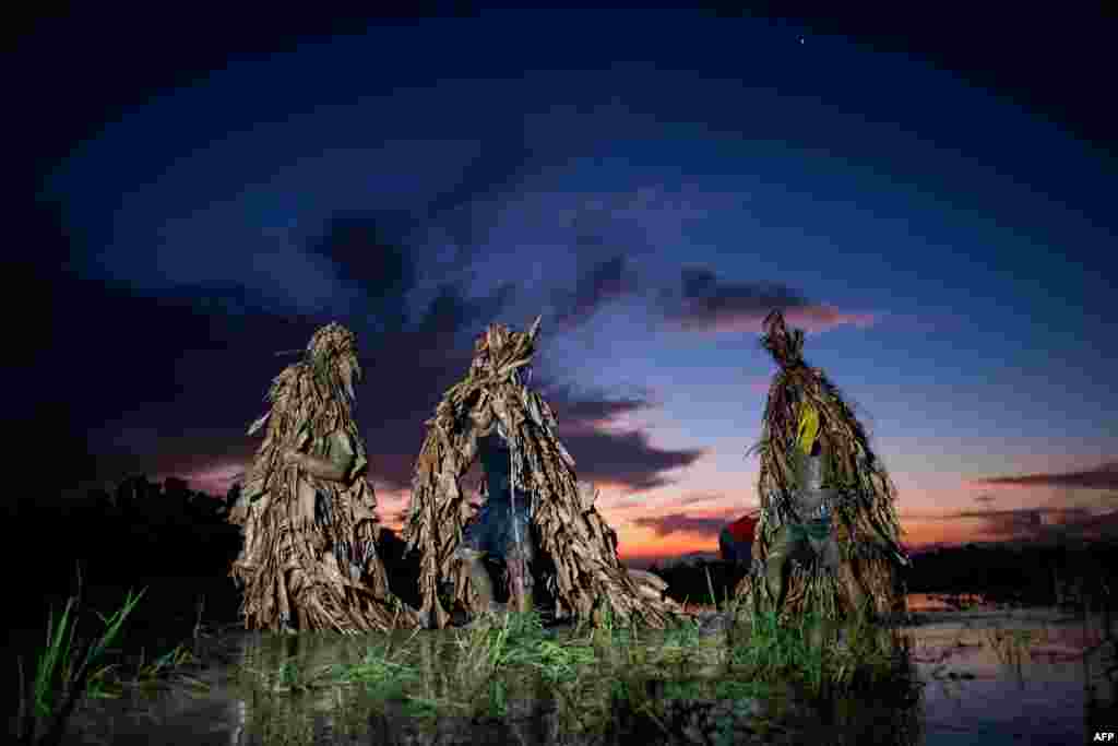 Devotees wear costumes made of banana leaves as they head to church to attend Mass as part of a religious festival, in honor of St. John the Baptist, also known locally as the "mud people" festival, in Aliaga town, Nueva Ecija province, north of Manila, Philippines.