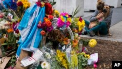FILE - Amy Biden, of New York, hugs her dog Smokey after placing flowers she brought to a makeshift memorial that honors victims of an attack who were struck and killed by a rental truck driven by indicted suspect Sayfullo Saipov last Tuesday, at Chambers and West Streets in New York, Nov. 4, 2017. 