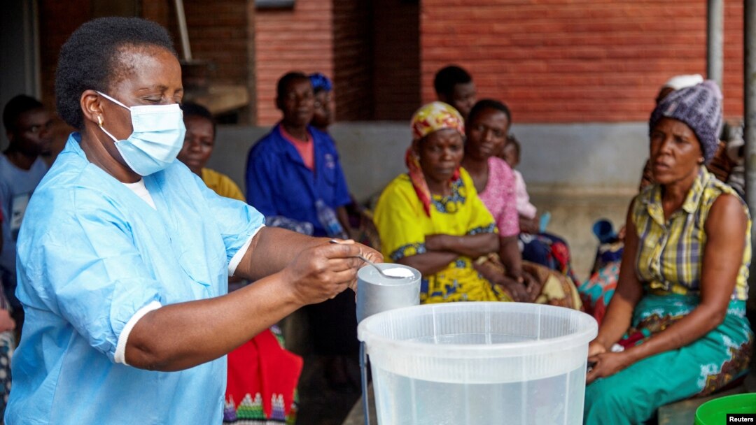 FILE - Violett Motta, a health surveillance assistant in Malawi, mixes chlorine with water to disinfect it at a health center in response to the latest cholera outbreak in Blantyre, Malawi, Nov. 16, 2022. 