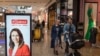 Shoppers walk past an electronic billboard showing a photo of New Zealand Prime Minister Jacinda Ardern in Christchurch, New Zealand, Oct. 14, 2020.