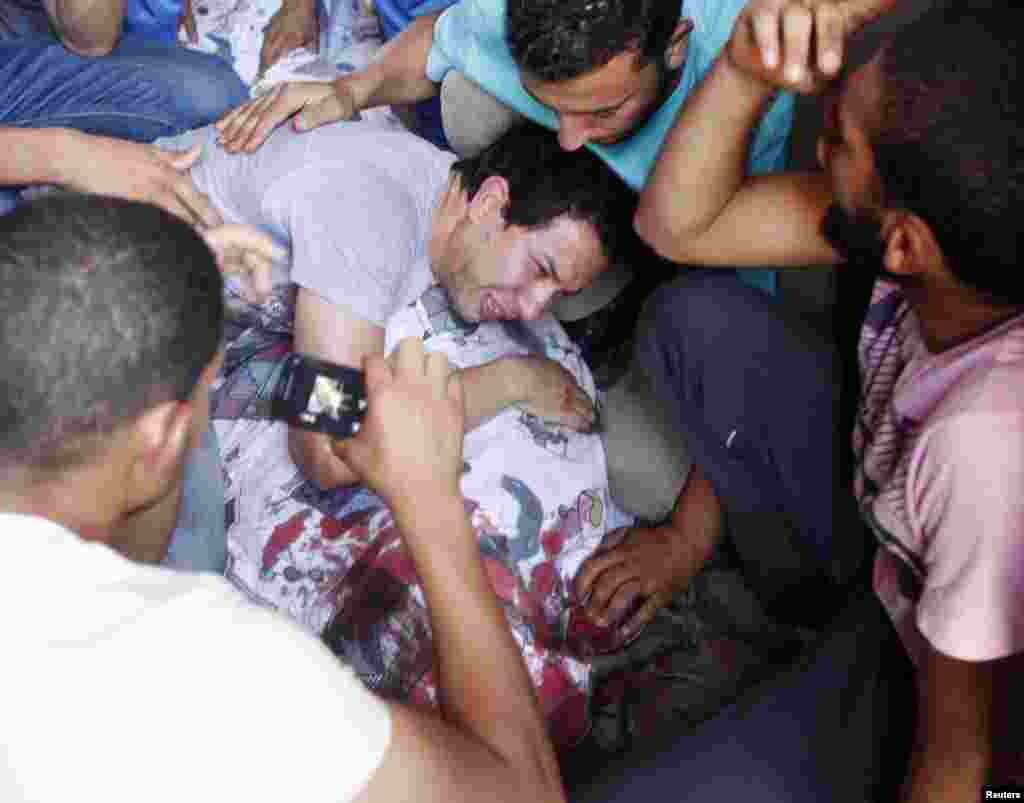 Supporters of former Egyptian President Mohamed Morsi gather around the covered body of a victim of clashes outside the Republican Guard building in Cairo, July 5, 2013. 