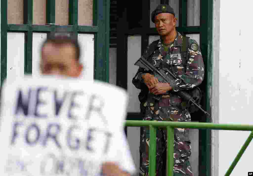 A soldier watches demonstrators protest President Rodrigo Duterte's Martial Law declaration for the southern Mindanao region, outside of the Philippine armed forces headquarters in Quezon city northeast of Manila.