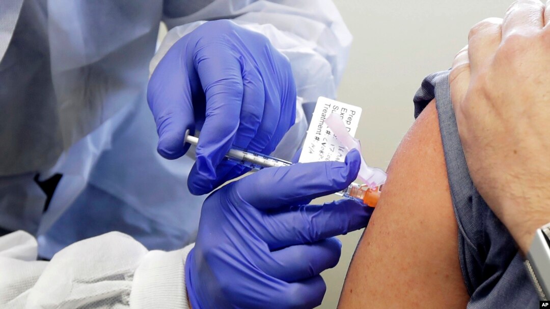 FILE - A man receives a shot in the first-stage safety study clinical trial of a potential vaccine for COVID-19, the disease caused by the new coronavirus, at the Kaiser Permanente Washington Health Research Institute in Seattle, March 16, 2020..