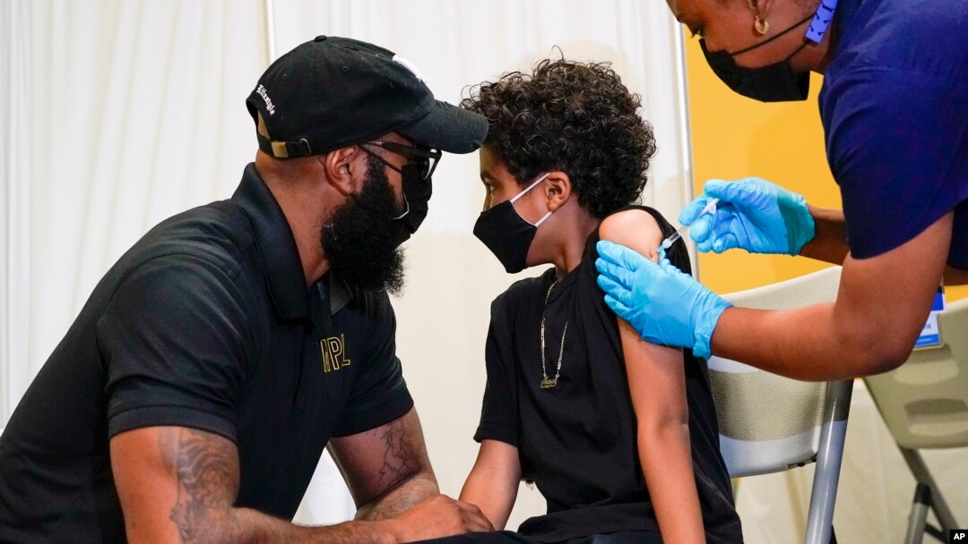 A father, left, comforts his son as he is inoculated with his first dose of a COVID-19 vaccine for children five to 12 years, at Public School 19 in the East Village neighborhood of New York City, Nov. 8, 2021. 