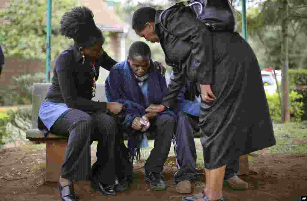 Stephen , katikati, aliyempoteza baba yake katika shambulizi kwenye maduka ya westgate mall akifarijiwa na ndugu wakati akisubiri uchunguzi wa mwili wa baba yake. 