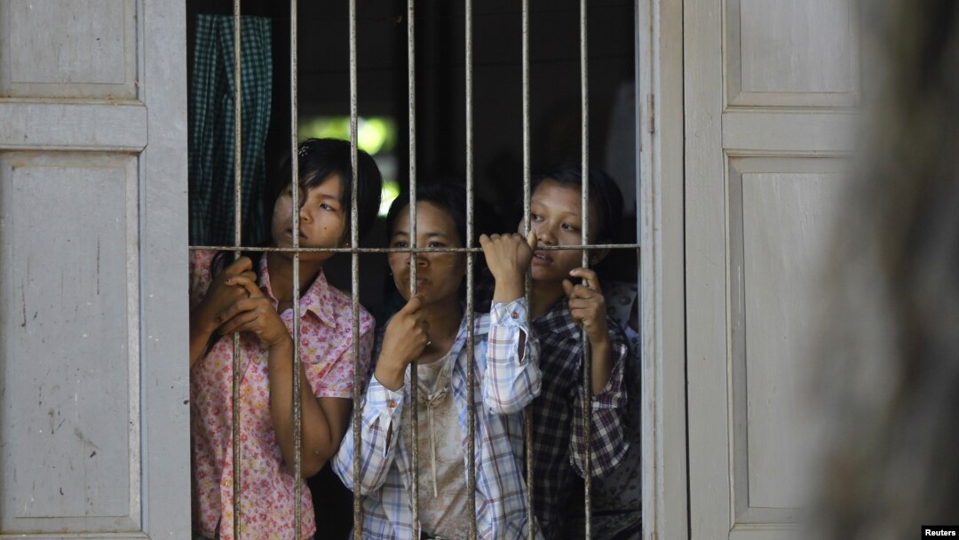 Burmese farmers look at police from inside a monastery in protest against the seizing of farmland across 26 villages for a copper mine project in Sarlingyi Township, September 12, 2012. 