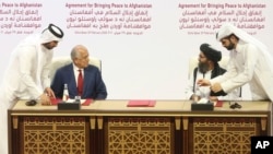 AQSh vakili Zalmay Xalilzod (chapda) va Tolibon yetakchilaridan biri Mulla Abdul G'ani Birodar tinchlik bitimini imzolamoqda, Doxa, Qatar, 2020-yil, 29-fevral
