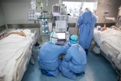 FILE - Medical staff treat COVID-19 coronavirus patients at a hospital in Wuhan, in China's central Hubei province, March 19, 2020.